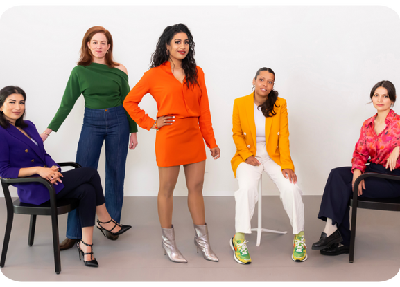 Five women in colorful business attire posing confidently in a bright studio, representing Trademarkhost — best trademark services.